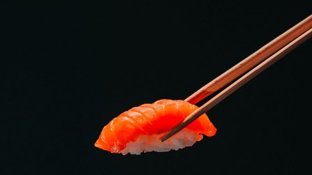 Sushi au saumon tenu par des baguettes