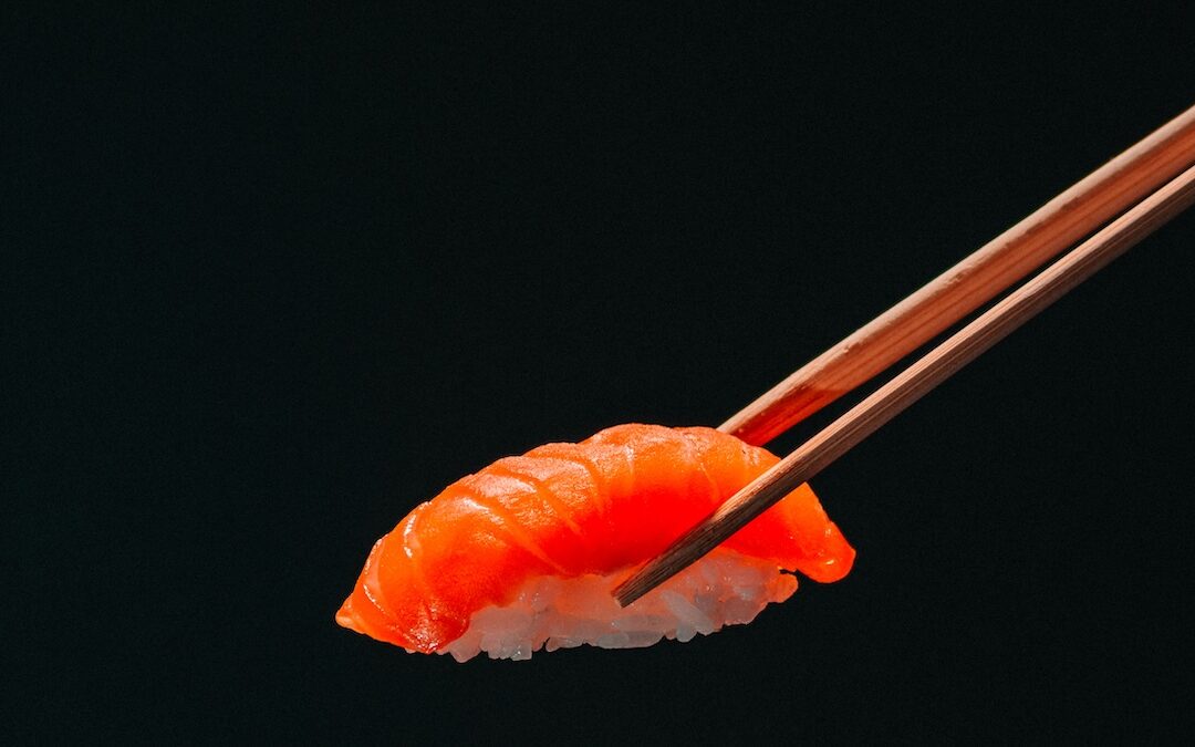 Sushi au saumon tenu par des baguettes