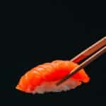 Sushi au saumon tenu par des baguettes